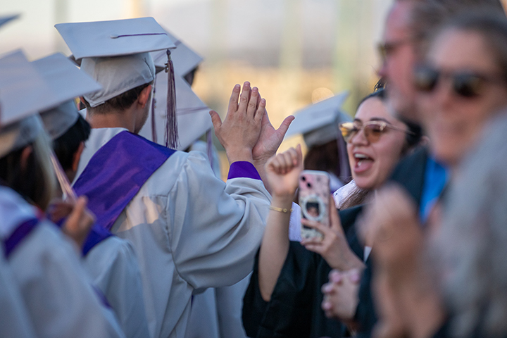 A graduate gives out a high five to someone in the crowd