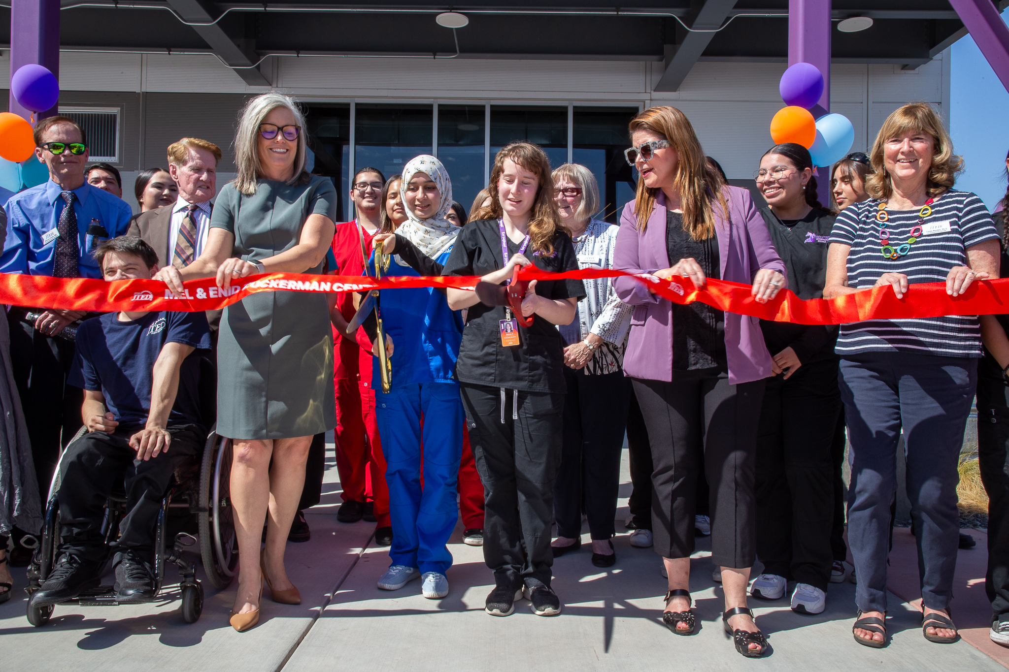 Students, staff and officials cut the red ribbon with giant scissors