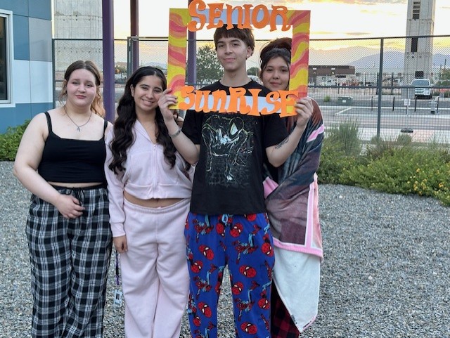 Four seniors pose with the Senior Sunrise photo frame