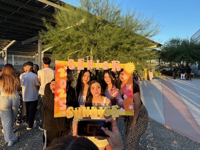 A group of seniors pose with the Senior Sunrise photo frame