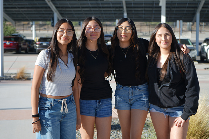 Four girls smile in front of the parking lot