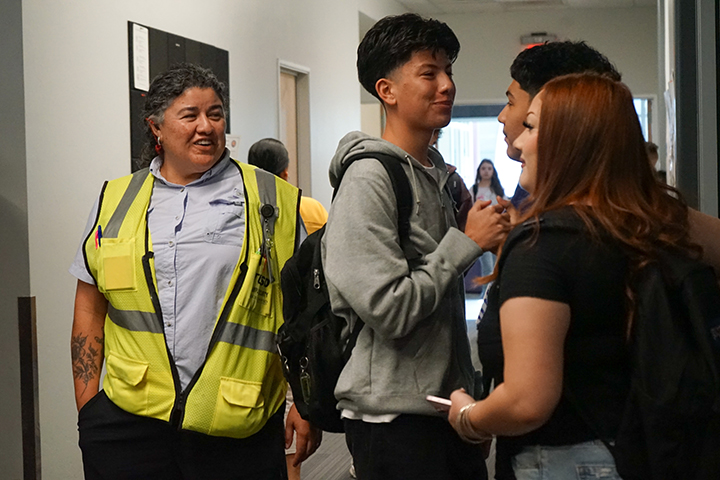 A hall monitor smiles at a group of students