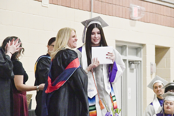 A graduate accepts her diploma from the principal