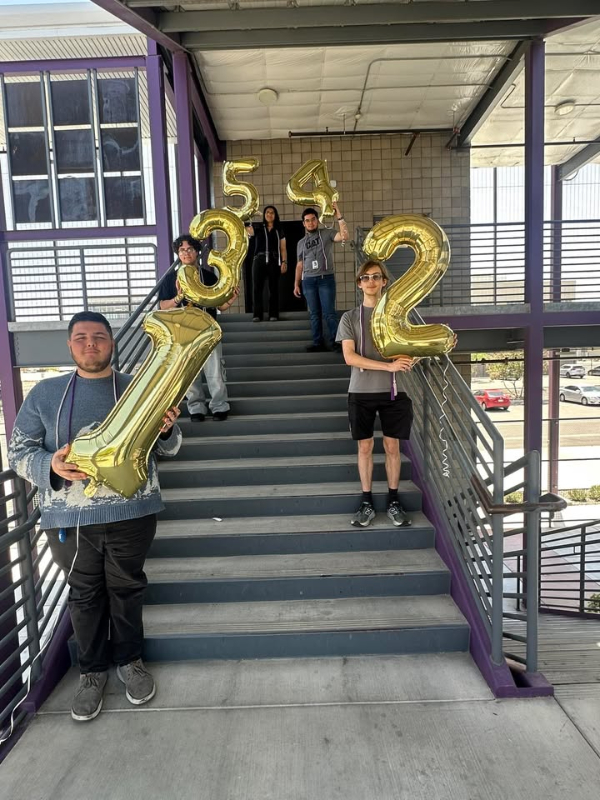 Five students hold number balloons on the stairs