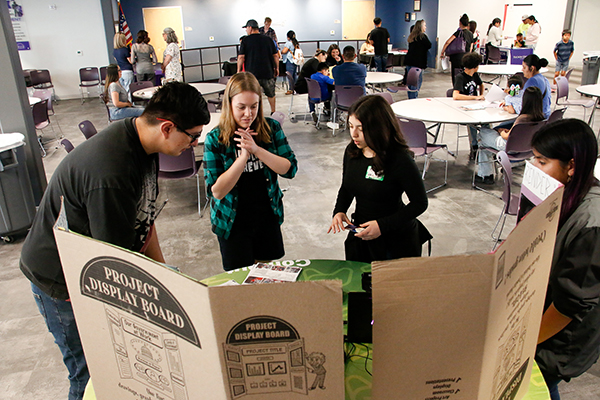 Students look at poster board projects