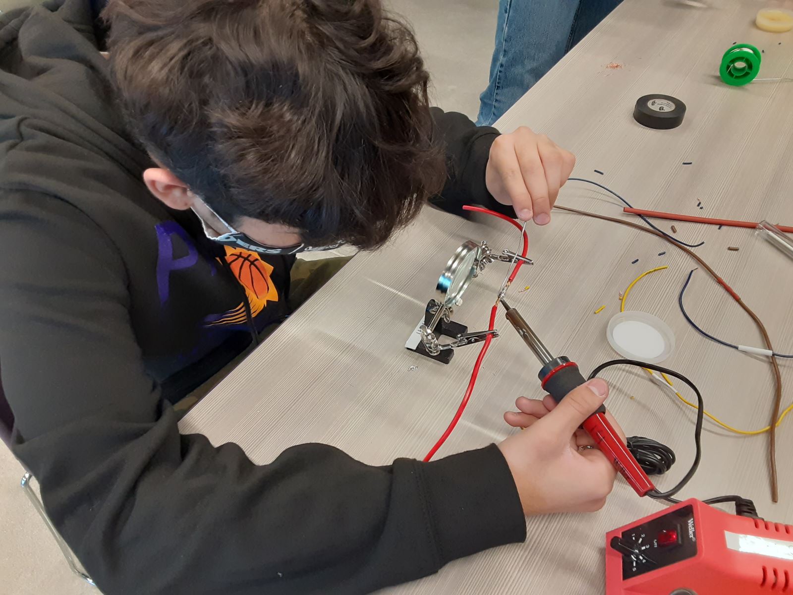 Student practices soldering skills in Automation and Robotics class.
